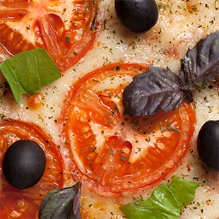 Closeup of pizza with tomatoes and black olives.